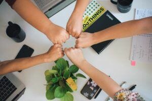 hands grouped together over a desk in a show of solidarity and teamwork