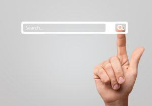 hand pointing to a search bar on a grey background