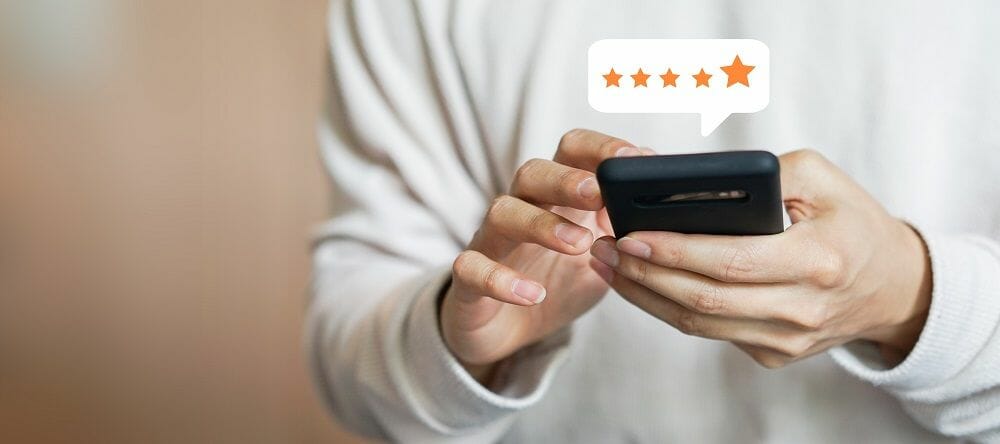a person's hands hold a smarthone with a 5 star google review popping over the screen